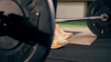 Spor salonunda siyah taytlı bir kız antrenör ağırlığıyla halteri kaldıracak.