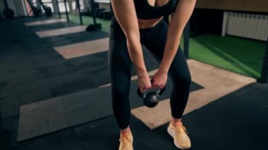 Spor salonunda siyah taytlı bir kız antrenör ve kilolu bir top.