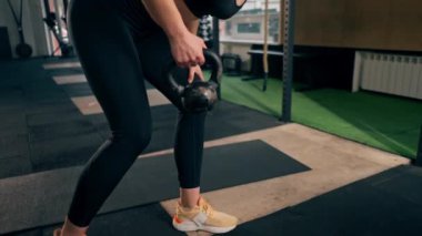 Spor salonunda siyah taytlı bir kız antrenör ve kilolu bir top.
