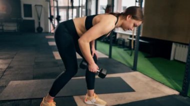 Spor salonunda siyah taytlı bir kız antrenör ve kilolu bir top.