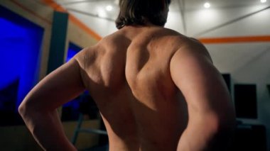Spor salonunda genç ve yakışıklı bir antrenör sırtını ısıtır belini bükerek ve bükerek sırtını gösterir.