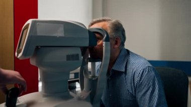 Optalmoloji kliniğinde yaşlı bir hastaya makine kullanılarak bir görme testi yapılır.
