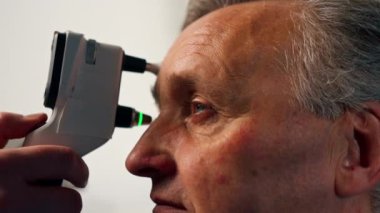 Bir göz hekimliği kliniğinde yaşlı bir hastanın göz bebeğinin basıncını kontrol ediyor.