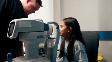 Bir göz doktoru kliniğinde küçük bir kız kırmızı ışık makinesiyle görme duyusunu teşhis edecek.