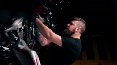 Bir motosiklet tamirhanesinde bir usta motorsikletin çekirdeğini tornavidayla söker.