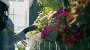 Çiçekçi dükkanının yanında çiçekli bir kız gerekli çiçekleri ve çiçek aranjmanını seçer.