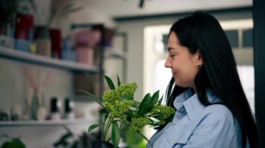 Çiçekçiyi kapatın. Beyaz bir masanın yanında bir kız çiçek demeti dolusu beyaz çiçek topluyor.