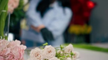 Çiçekçi bir kız beyaz bir masanın yanında güzel bir buket beyaz çiçek topluyor.