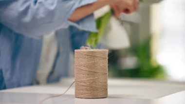 Çiçekçide bir çiçekçi beyaz bir kağıt ambalajla ihaleyi sarar ve halatla ipi keser.