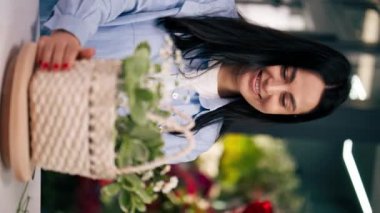 dikey video bir çiçekçide kapanır beyaz bir masanın yakınındaki bir kız bir çiçek aranjmanı toplar sepetteki bir buketi