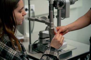Bir göz bilimi kliniğinde genç bir doktor genç bir kızla vizyon hakkında bir konsültasyon yapar.
