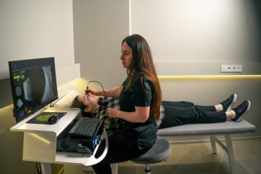 Bir göz hekiminde genç bir doktor genç bir kızın gözünün ultrasonunu çeker.