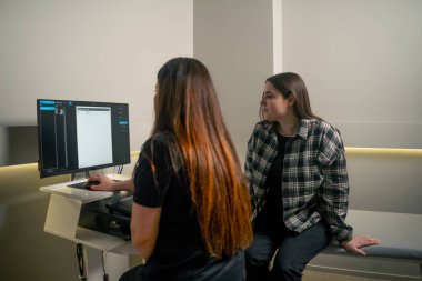 Göz muayenesinde genç bir doktor göz ultrasonundan sonra sonuçları bir kıza gösterir.