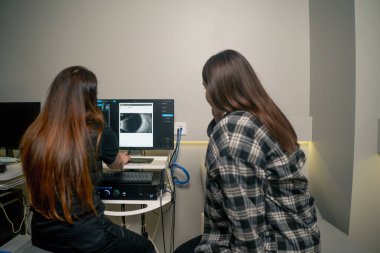 Göz muayenesinde genç bir doktor göz ultrasonundan sonra sonuçları bir kıza gösterir.