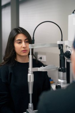 Bir göz doktoru kliniğinde yaşlı bir doktor genç bir kızla vizyon hakkında bir danışma yapıyor.