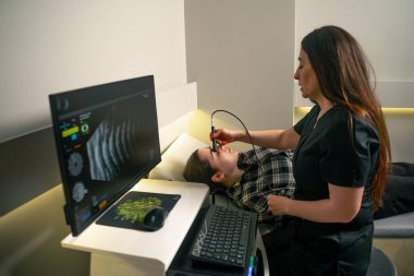 Bir göz hekiminde genç bir doktor genç bir kızın gözünün ultrasonunu çeker.