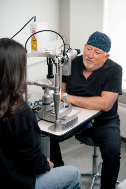 Bir göz doktoru kliniğinde yaşlı bir doktor genç bir kızla vizyon hakkında bir danışma yapıyor.