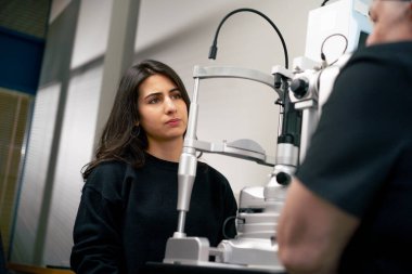 Bir göz doktoru kliniğinde yaşlı bir doktor genç bir kızla vizyon hakkında bir danışma yapıyor.