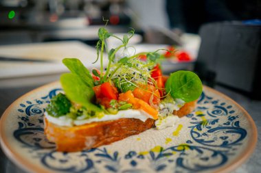 Profesyonel bir mutfakta, kalıplı tabakta somon ve bitkilerle hazır tost var.