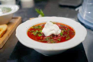 Profesyonel bir mutfakta, beyaz bir tabakta, ekşi krema ve otlarla yakın plan.