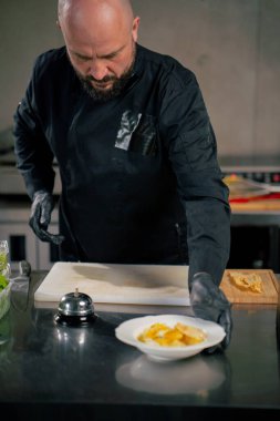 Profesyonel bir mutfakta beyaz bir tabakta hazır carbonara makarnasında şef siparişi verir.