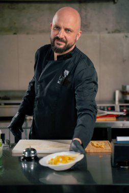 Profesyonel bir mutfakta beyaz bir tabakta hazır carbonara makarnasında şef siparişi verir.