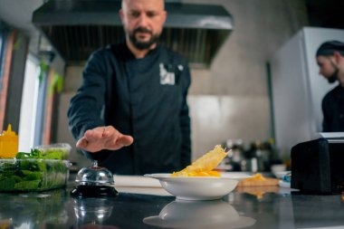 Profesyonel bir mutfakta beyaz bir tabakta hazır carbonara makarnasında şef siparişi verir.