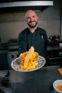 Profesyonel bir mutfakta beyaz bir tabakta hazır peynirli tost. Şef siparişi veriyor.