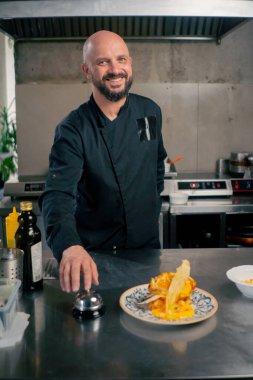 Profesyonel bir mutfakta beyaz bir tabakta hazır peynirli tost. Şef siparişi veriyor.