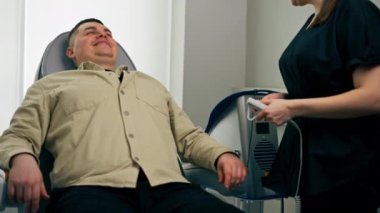Bir kozmetoloji kliniğinde bir kız kozmetikçi bir erkekle ilk muayeneyi yapar.