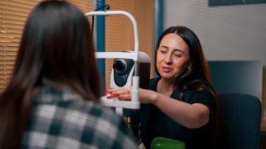 Bir göz hekiminde genç bir doktor büyüteçle genç bir kıza teşhis koyuyor.