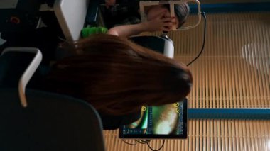 Optalmoloji kliniğinde çekilen dikey videoda genç bir doktor büyüteç takan genç bir kıza teşhis koydu.