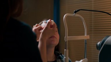 Optalmoloji kliniğine yakın plan çekimde kızın gözüne dondurucu damlalar konur.