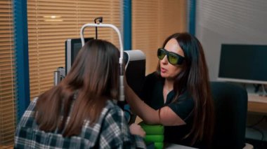 Bir göz hekiminde genç bir doktor büyüteç lazer düzeltmesi ile genç bir kıza teşhis koyuyor.