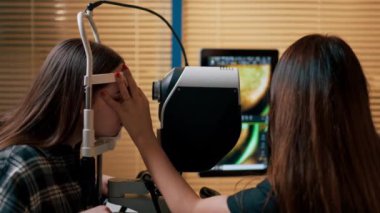 Bir göz hekiminde genç bir doktor büyüteç lazer düzeltmesi ile genç bir kıza teşhis koyuyor.