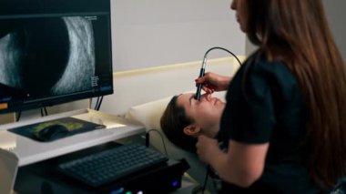 Bir göz hekiminde genç bir doktor genç bir kızın gözünün ultrasonunu çeker.