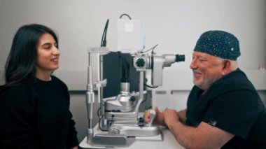 Bir göz doktoru kliniğinde yaşlı bir doktor genç bir kızla vizyon hakkında bir danışma yapıyor.