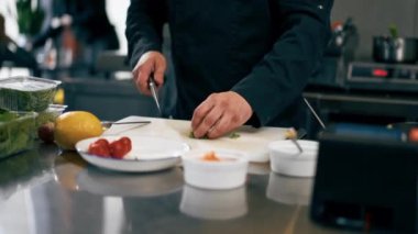 Profesyonel bir mutfakta siyah ceketli bir şef tost için somon balığı keser.