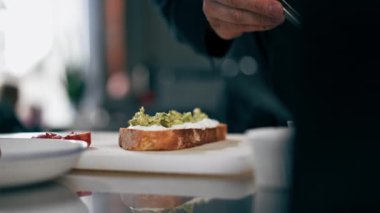Siyah ceketli profesyonel bir mutfak şefinin yanına somon balığını cımbızla tost yapar.