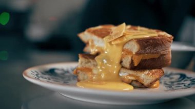 Profesyonel bir mutfakta peynir ve sıvı peynirle desenli bir tabağın yakın çekimi.