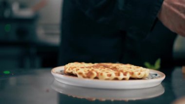 Profesyonel bir mutfakta siyah ceketli bir şef Belçika waffle 'ı yapıyor.
