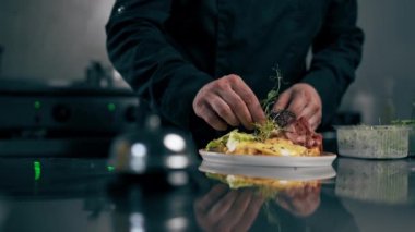 Profesyonel bir mutfakta siyah ceketli bir şef Belçika usulü bir waffle süsler.