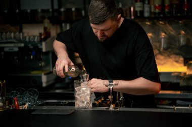 Barmen, barmene içki dolduruyor. Barmen ölçü kabına alkol dolduruyor.