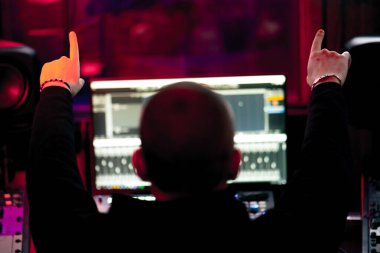 Kayıt odasının karanlığında stüdyoda neon ışıkla birlikte ses mühendisi konsolda çalışır sesi ayarlar ve sesi karıştırır.