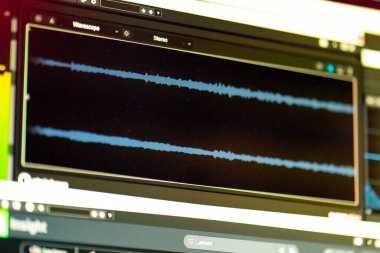 Karanlık bir kayıt stüdyosunda ses kaydı, temizlik, karıştırma ve işleme sesi olan bir monitör profesyoneller için özel bir programda.
