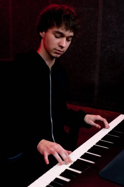 Kayıt odasında, stüdyoda ses mühendisi arzulanan anahtarı seçen sentezleyicinin sesini dinlerken,