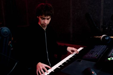 Kayıt odasında, stüdyoda ses mühendisi arzulanan anahtarı seçen sentezleyicinin sesini dinlerken,