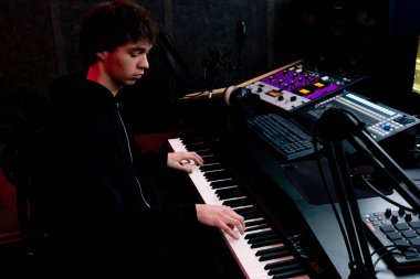 Kayıt odasının karanlığında stüdyoda neon ışıkla birlikte ses mühendisi konsolda çalışır sesi ayarlar ve sesi karıştırır.