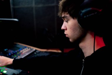 Kayıt odasının karanlığında stüdyoda neon ışıkla birlikte ses mühendisi konsolda çalışır sesi ayarlar ve sesi karıştırır.