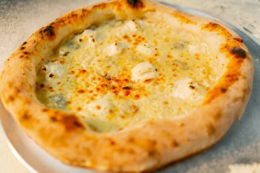 Profesyonel bir mutfağa yakın plan. Masada yeni hazırlanmış pizza var.